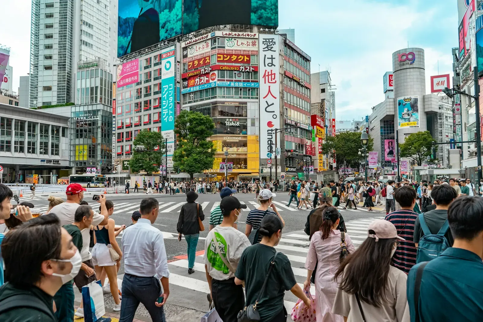 Crowds crossing Shibuya Crossing surrounded by buildings in Tokyo